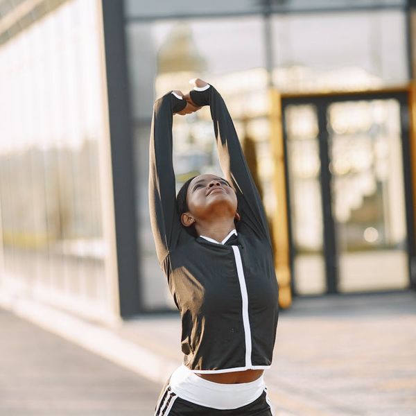 Energetic woman smiling and stretching outdoors, feeling full of vitality.
